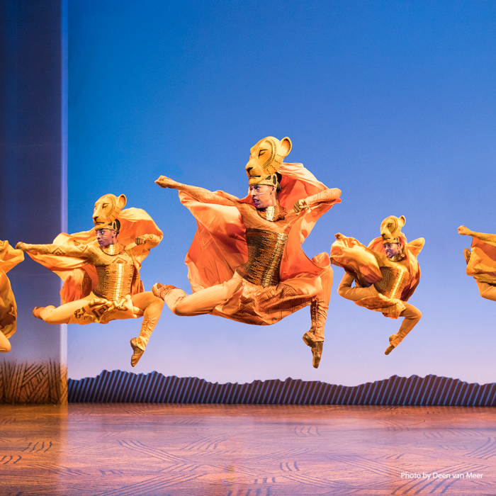 a group of people jumping in the lion king scene