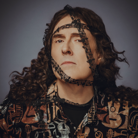 Weird Al looking at the camera with musical tap around his head