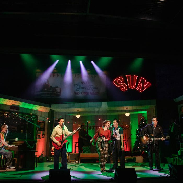 Millon dollar band on stage with a green and red holiday background setting