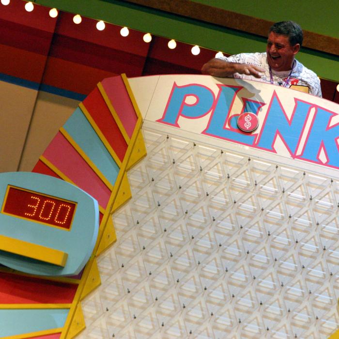 A man at the top of the Price is Right Plinko game ready to play