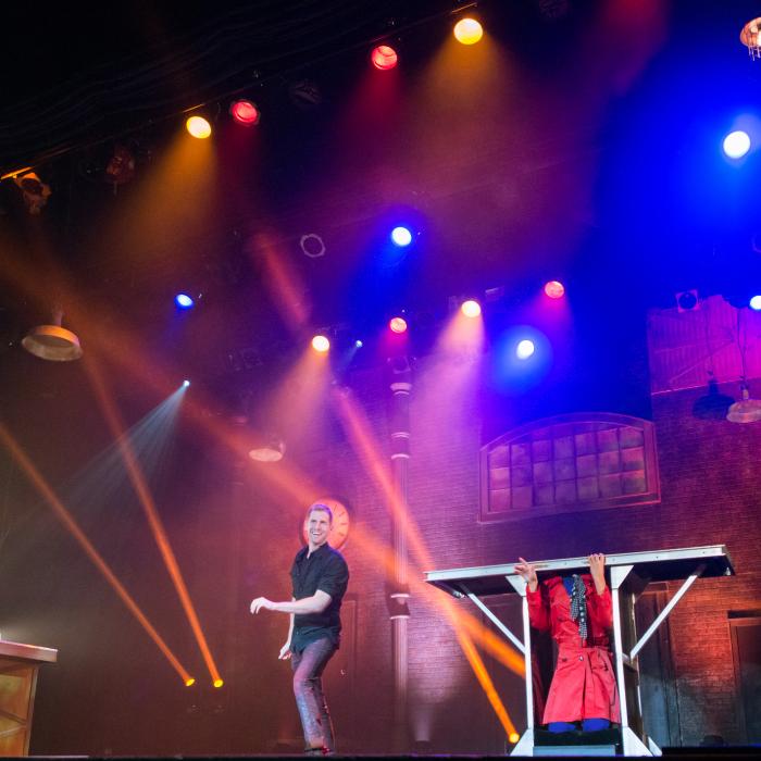 Rob Lake on stage with a pink, blue and purple colored light illuminating the stage