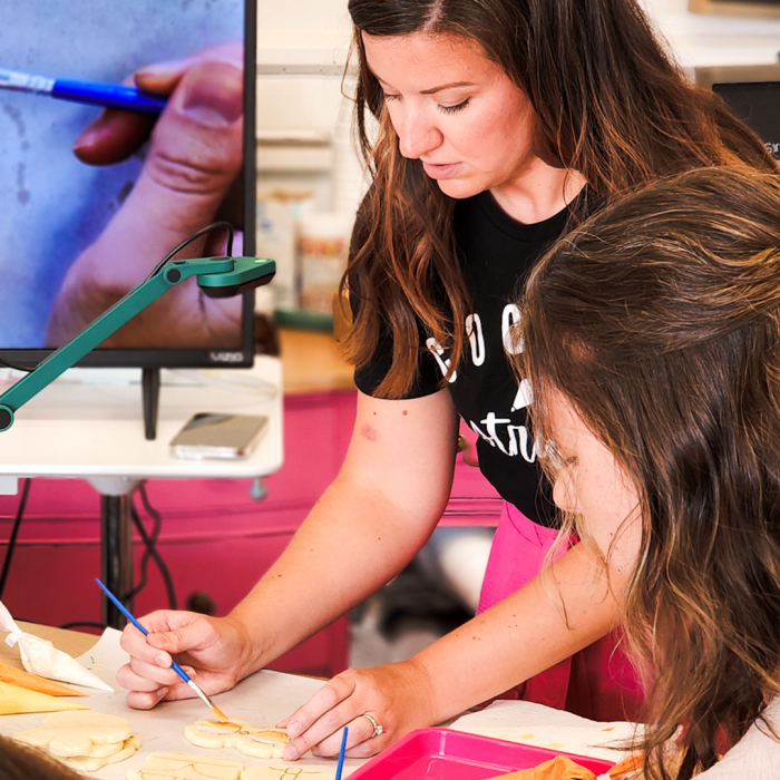 Lady showing a student how to decorate a cookie