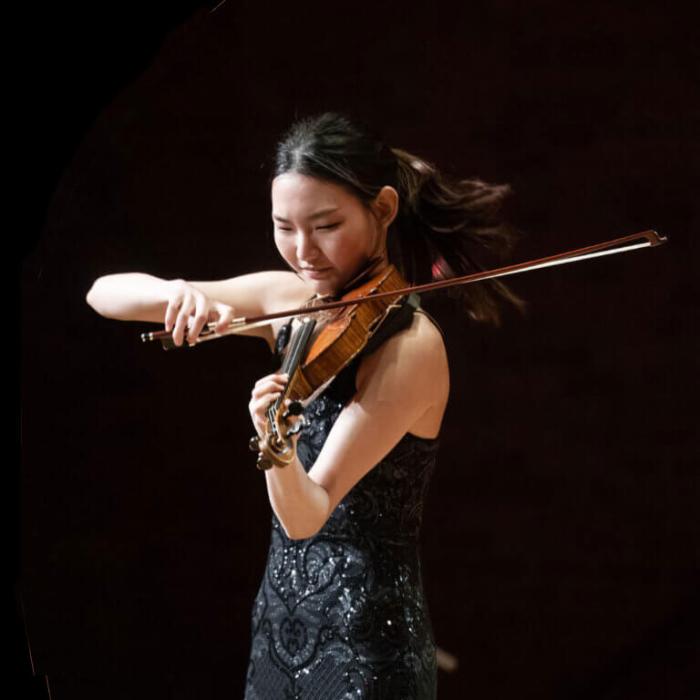 A young Asian lady playing the violin on a black background