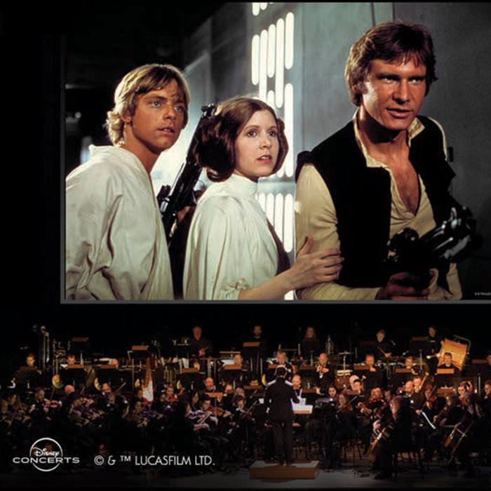 A movie scene of Luke Skywalker, Princess Leah and Han Solo holding guns on a movie screen with a symphony playing the music underneath.