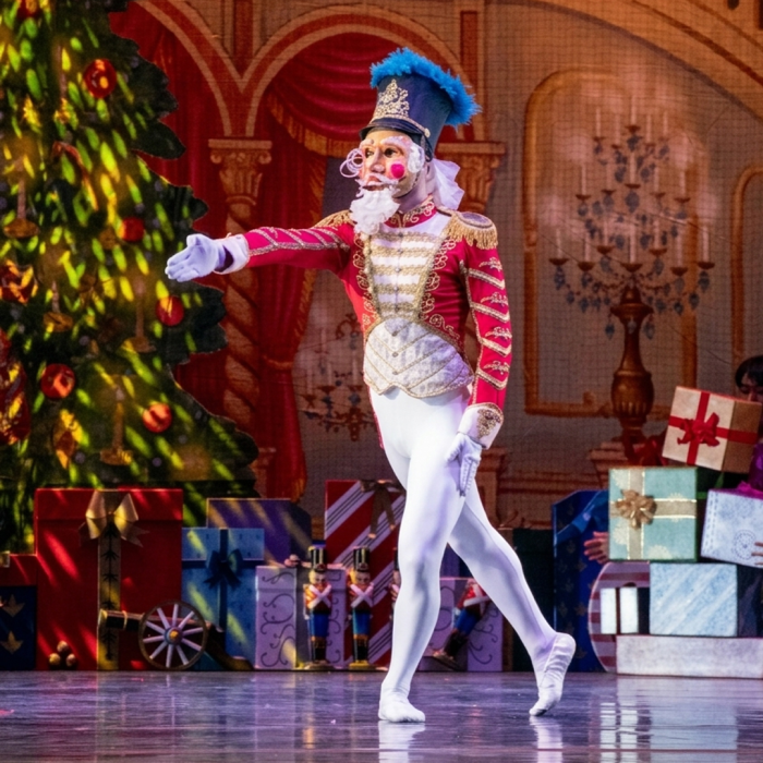 Nutcracker on stage with hand extended.