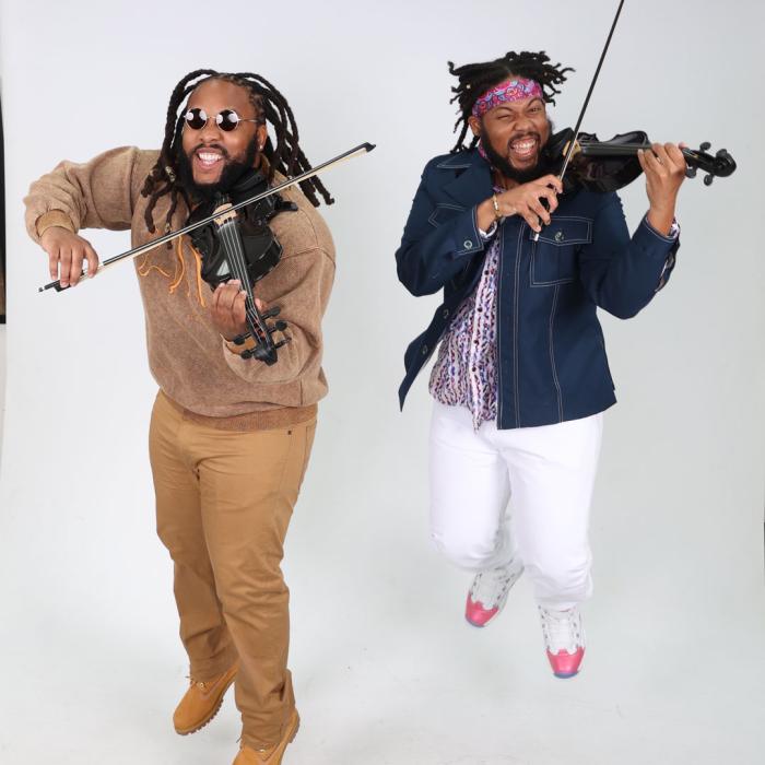 Promotional photo of Sons of Mystro with two black men playing their violins with excitement.