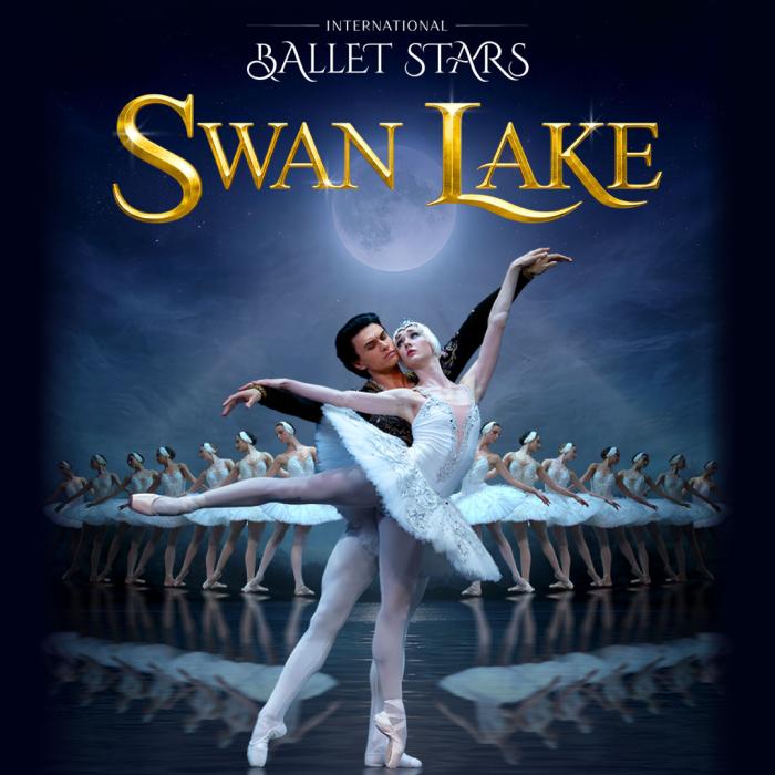 Ballerina couple embraced with the main in the back and the lady dressed as a swan in a white tutu.