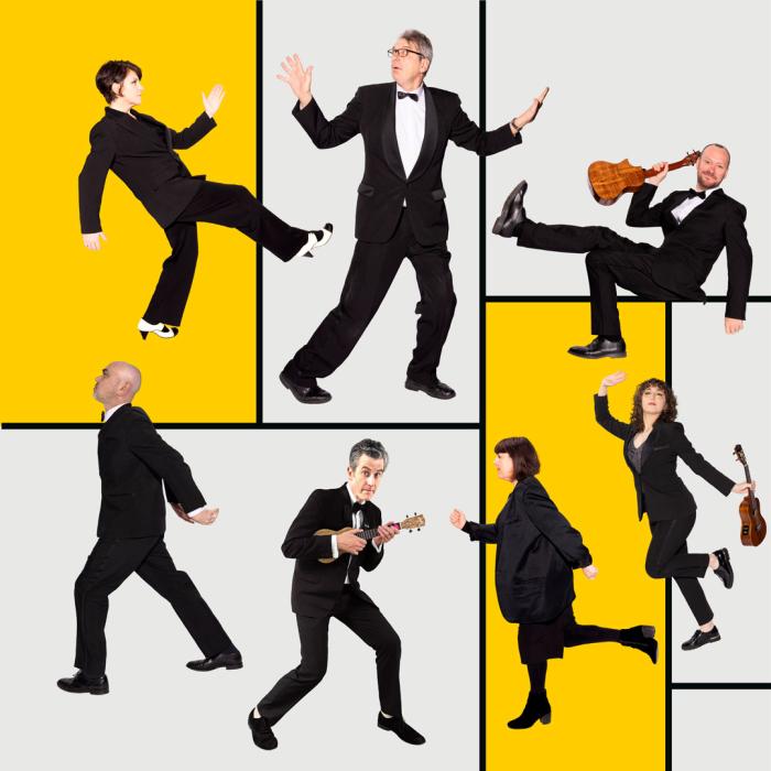 4 men and three women on a checkered grey and yellow background some of which are holding instruments.
