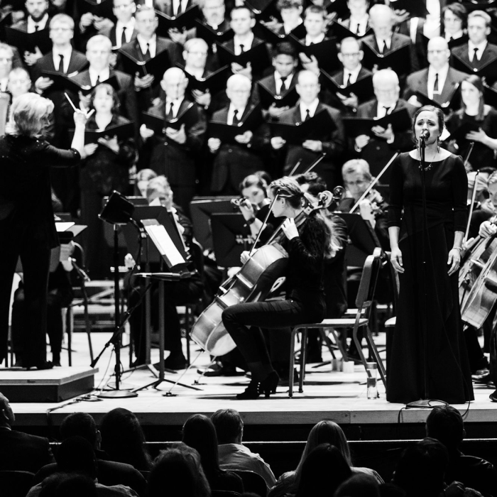 Lady singing with choir behind her