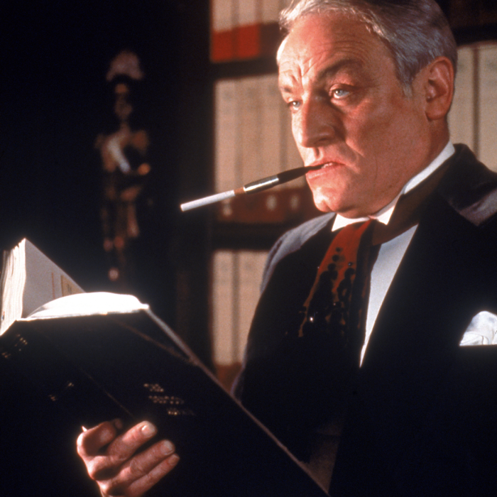 Man in a tux smoking and holding a book