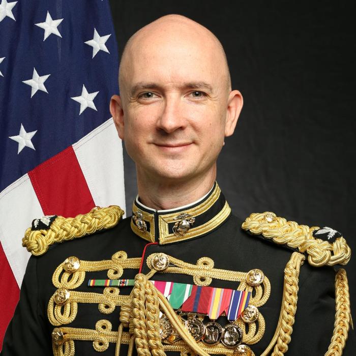 photo of the conductor in front of a flag